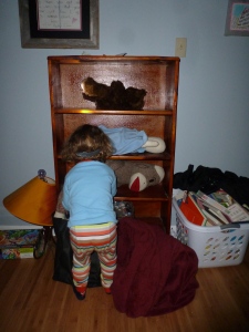 little boy with headlamp putting dolls on shelves of bookself